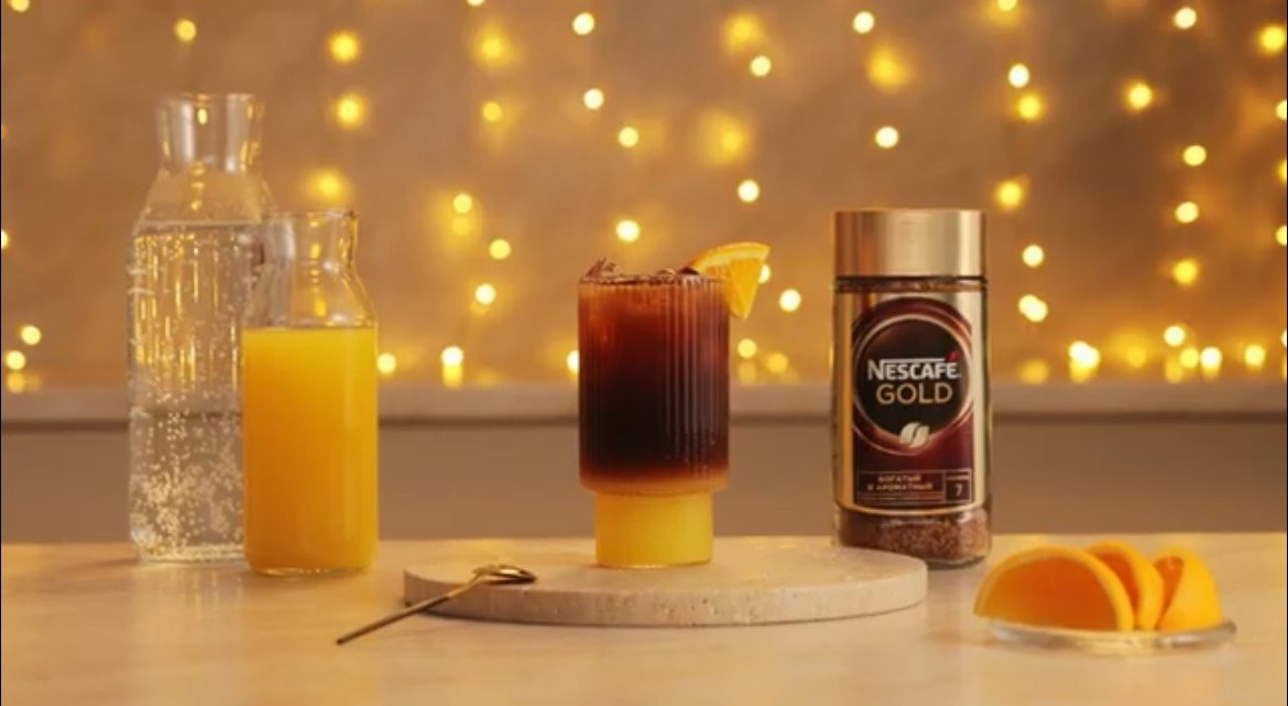 Кадр со съёмки Nescafé Gold: стакан с кофе и апельсиновым соком на фоне гирлянды